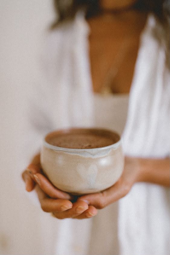 Hands holding a ceramic cup of cacao