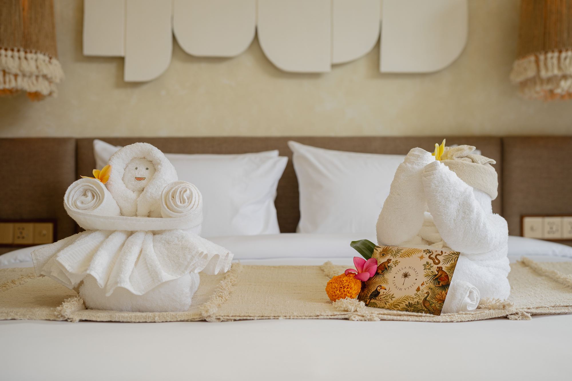 Welcome towels with a frangipani flower and card on the bed